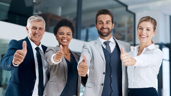 Four persons smiling with thumbs up