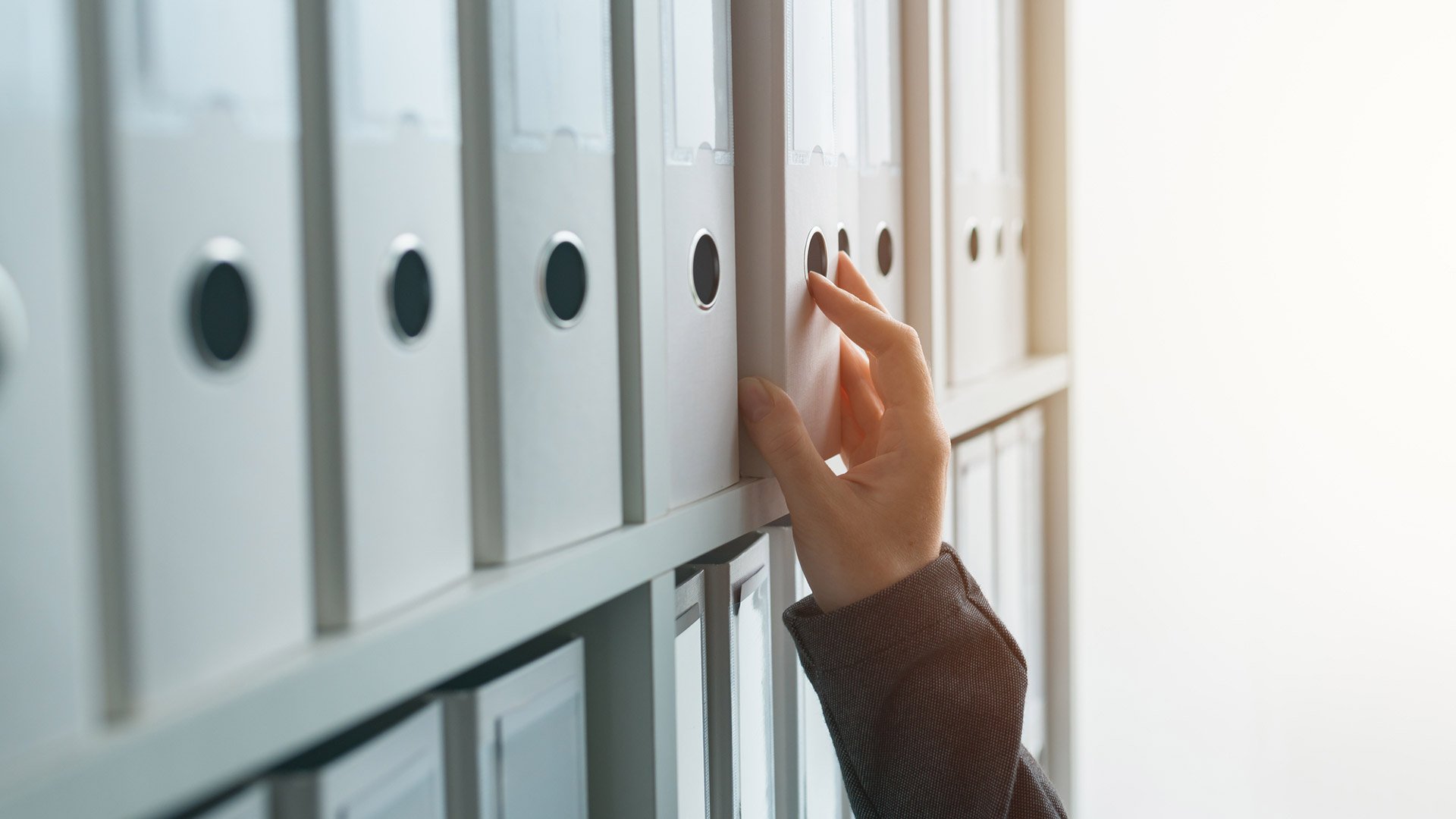 Hand pulls a folder from the shelf