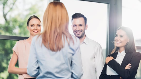 Four people stand together smiling at each other